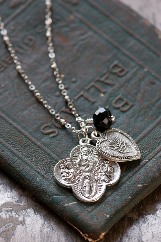 Silver sacred heart and miraculous medallion pendant necklace on vintage book